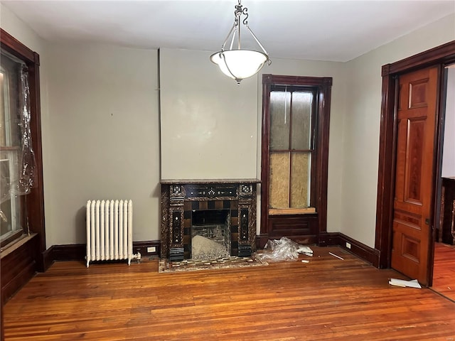 living room featuring a fireplace, radiator heating unit, and wood-type flooring