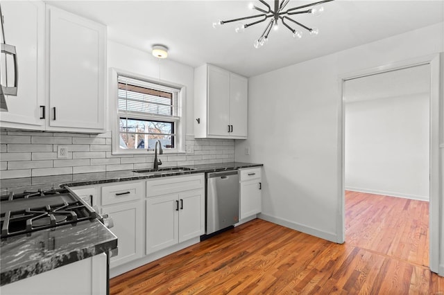 kitchen with backsplash, stainless steel dishwasher, sink, hardwood / wood-style flooring, and white cabinets