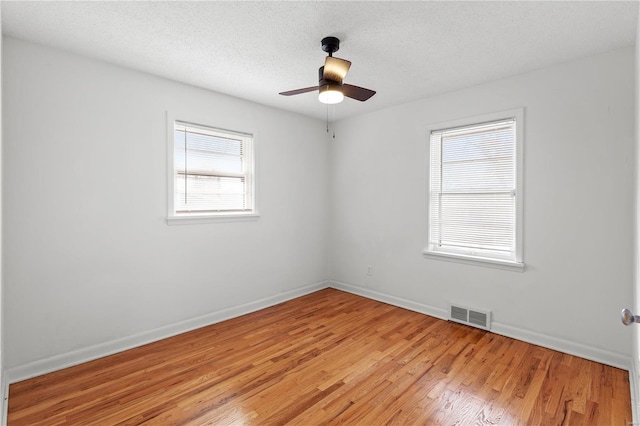 unfurnished room featuring a textured ceiling, a wealth of natural light, and light hardwood / wood-style flooring