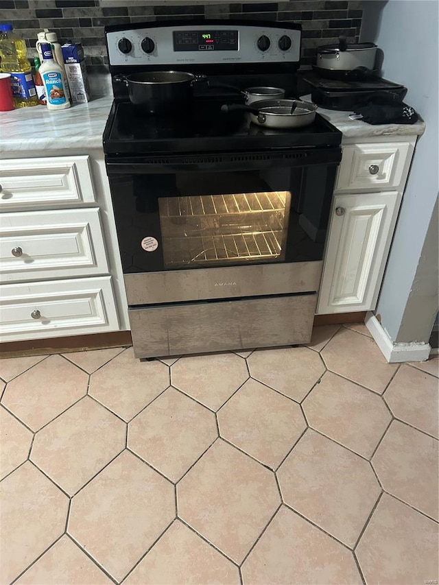 details with white cabinets, decorative backsplash, and stainless steel range with electric cooktop