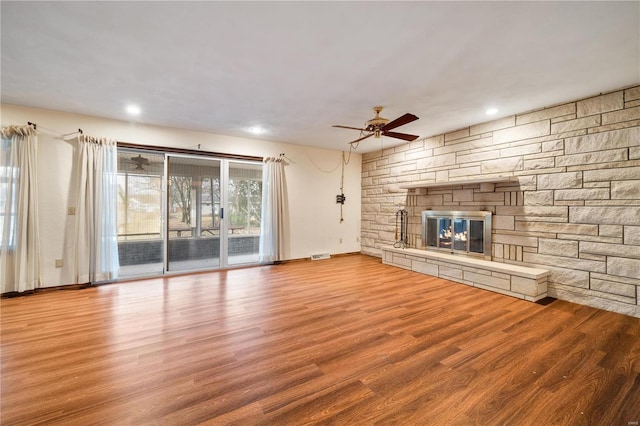 unfurnished living room with light hardwood / wood-style flooring, ceiling fan, and a stone fireplace