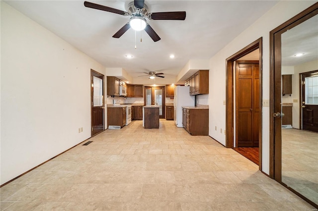 kitchen with white appliances, a kitchen island, and ceiling fan