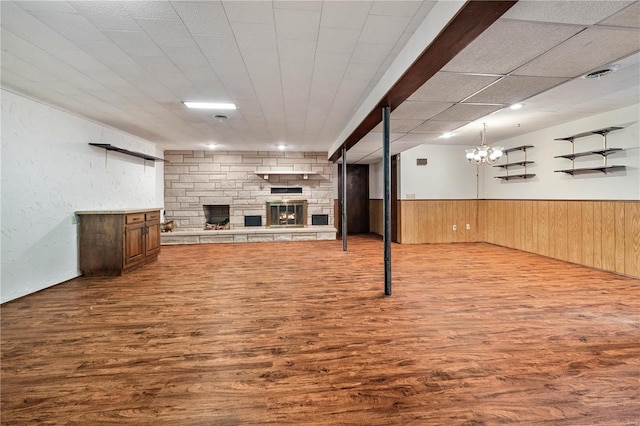 basement featuring hardwood / wood-style floors, a notable chandelier, wood walls, and a fireplace