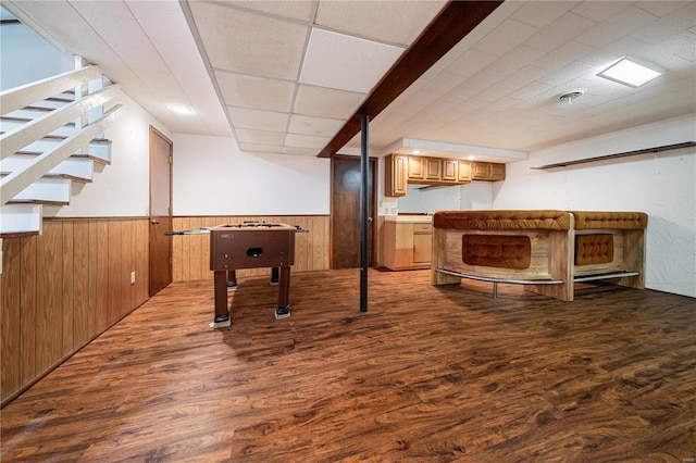 playroom with a paneled ceiling, wood walls, and hardwood / wood-style flooring