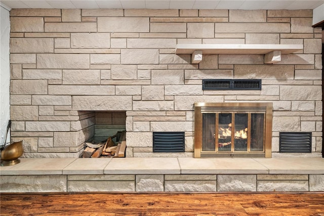 interior details with a stone fireplace and wood-type flooring