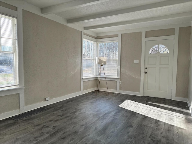 entrance foyer featuring beam ceiling, a wealth of natural light, and dark wood-type flooring