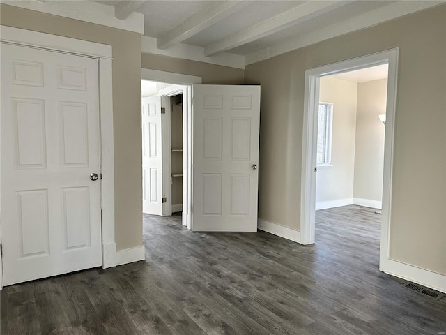 unfurnished bedroom with beam ceiling, dark hardwood / wood-style floors, and a closet