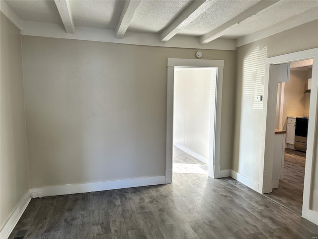 spare room featuring beamed ceiling, dark hardwood / wood-style flooring, and a textured ceiling