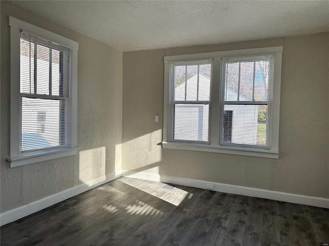 unfurnished room with a textured ceiling, dark hardwood / wood-style flooring, and a wealth of natural light