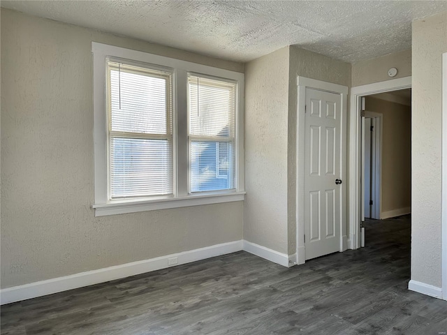 empty room with dark hardwood / wood-style flooring and a textured ceiling