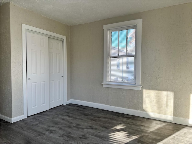 unfurnished bedroom featuring dark hardwood / wood-style flooring and a closet