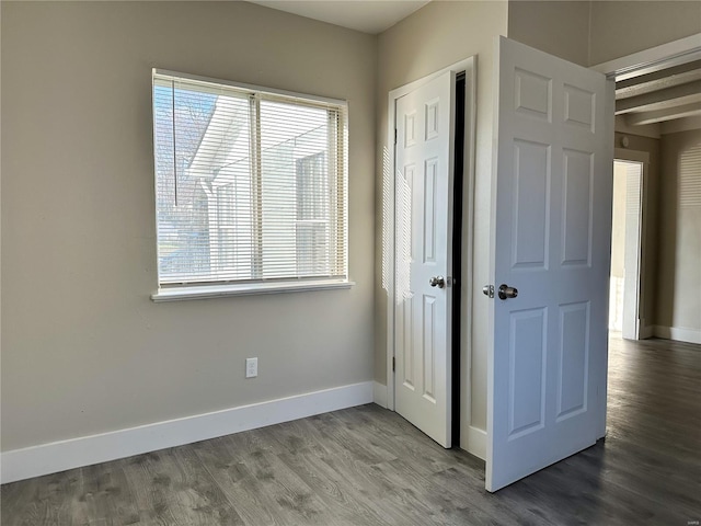 unfurnished bedroom with hardwood / wood-style floors and beam ceiling