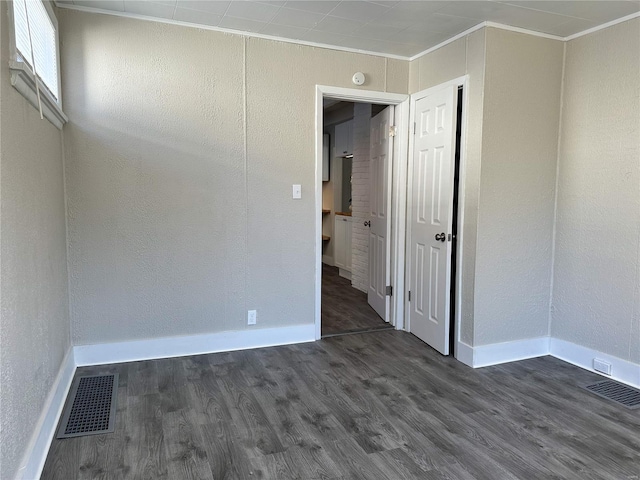 spare room featuring dark hardwood / wood-style floors and crown molding