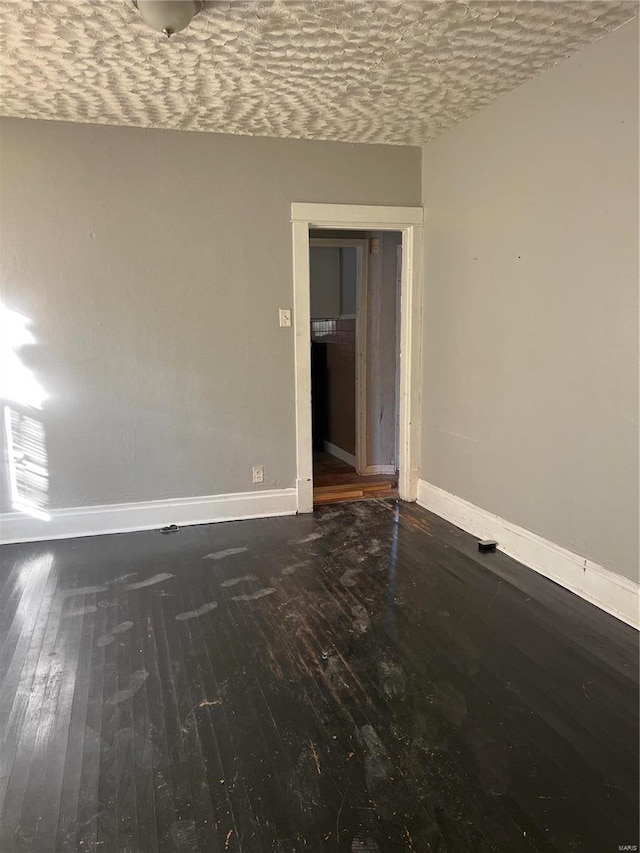 unfurnished room with dark hardwood / wood-style flooring and a textured ceiling