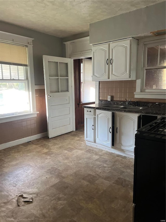 kitchen with white cabinets, sink, black range with electric cooktop, and a textured ceiling