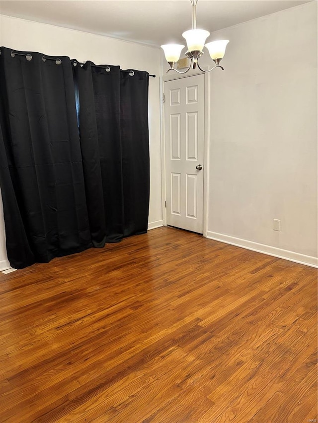 spare room featuring hardwood / wood-style floors and a chandelier