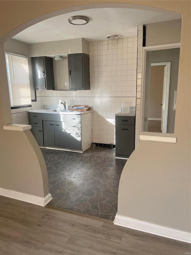 kitchen featuring gray cabinetry, sink, dark wood-type flooring, and tile walls