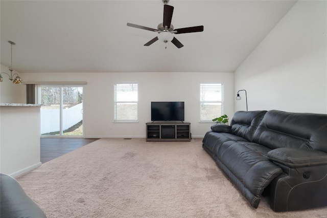 carpeted living room featuring lofted ceiling and ceiling fan with notable chandelier