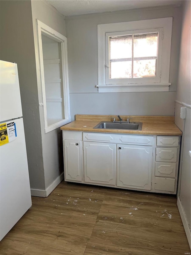 kitchen with white cabinets, white refrigerator, dark hardwood / wood-style flooring, and sink