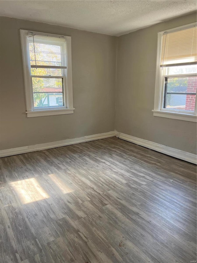 spare room with a textured ceiling and dark hardwood / wood-style floors