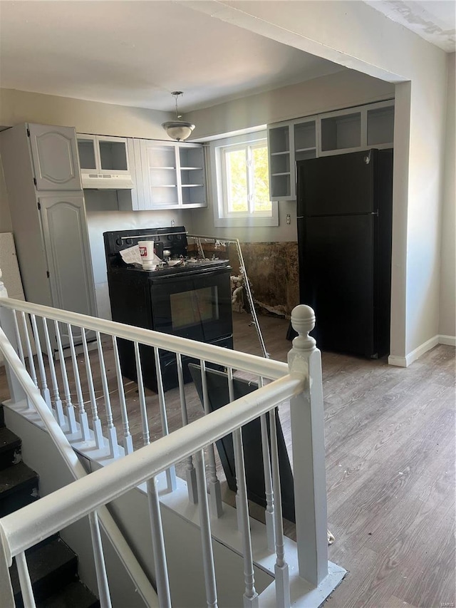 kitchen featuring white cabinets, pendant lighting, light hardwood / wood-style floors, and black appliances