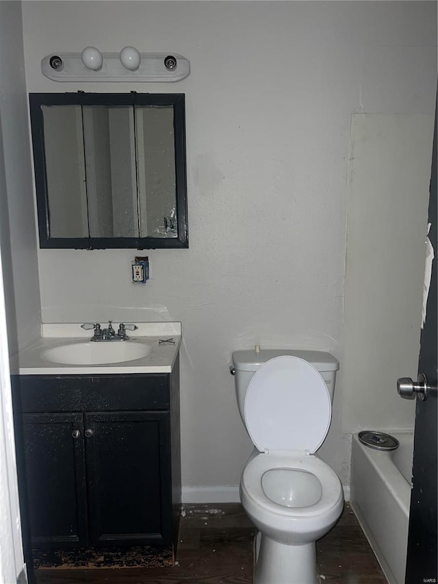 bathroom with hardwood / wood-style flooring, vanity, toilet, and a tub