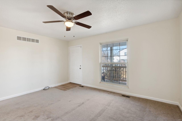 carpeted empty room featuring ceiling fan and a textured ceiling