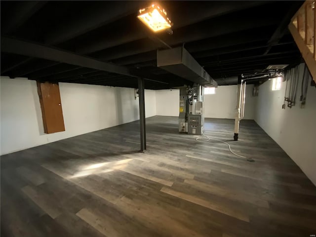 basement featuring heating unit and dark wood-type flooring