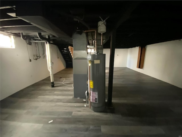 basement featuring heating unit, wood-type flooring, and gas water heater