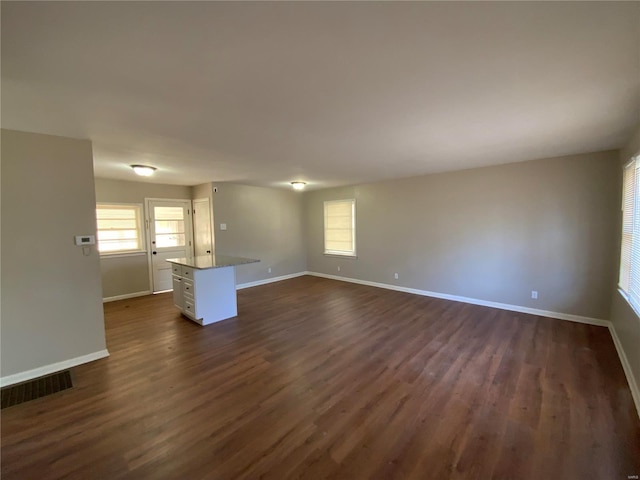 unfurnished living room with a healthy amount of sunlight and dark hardwood / wood-style flooring