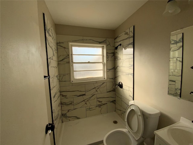 bathroom featuring a tile shower, vanity, and toilet