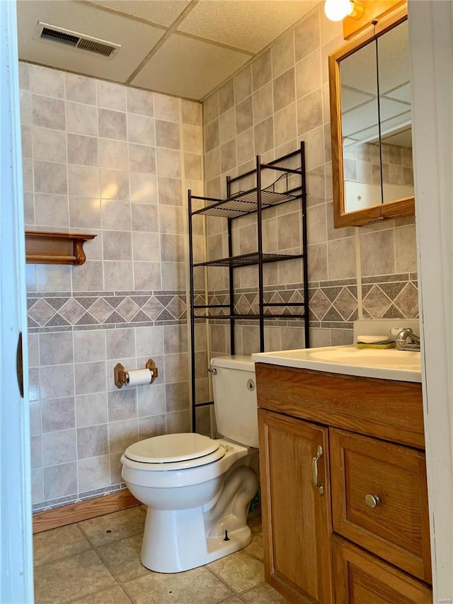 bathroom featuring tile patterned flooring, vanity, tile walls, and toilet