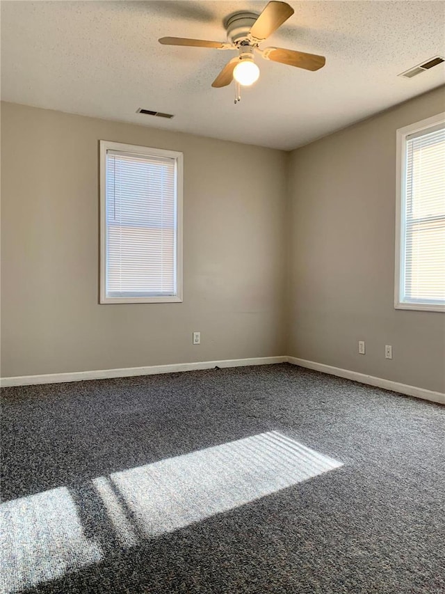 carpeted spare room featuring a textured ceiling and ceiling fan