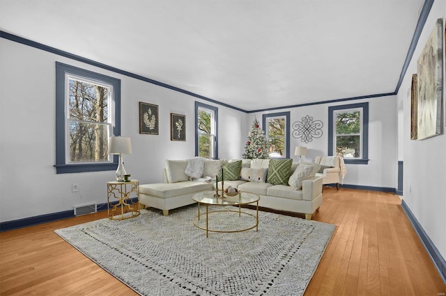 living room with a wealth of natural light, hardwood / wood-style floors, and ornamental molding