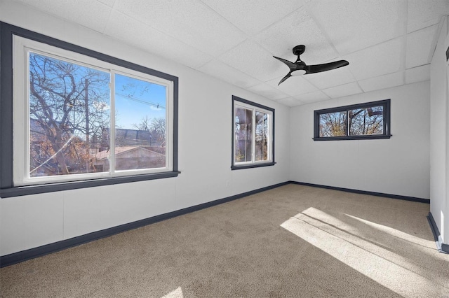 empty room with a paneled ceiling, ceiling fan, and carpet