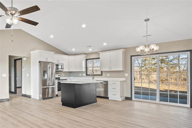 kitchen featuring decorative light fixtures, a center island, light hardwood / wood-style flooring, stainless steel appliances, and white cabinets