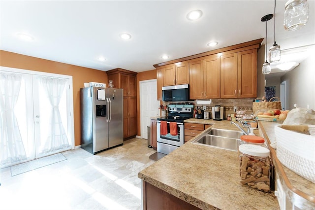 kitchen with backsplash, decorative light fixtures, sink, and appliances with stainless steel finishes