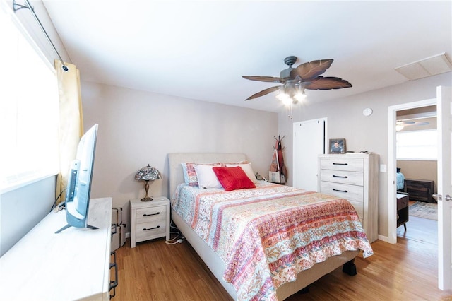 bedroom with hardwood / wood-style floors, ceiling fan, and multiple windows