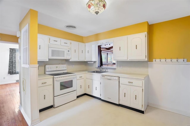 kitchen with white cabinetry, light hardwood / wood-style flooring, white appliances, and sink