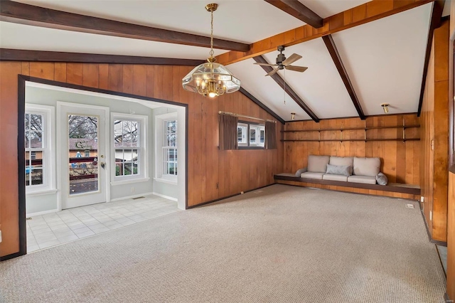 interior space featuring vaulted ceiling with beams, wood walls, light tile patterned flooring, and ceiling fan with notable chandelier