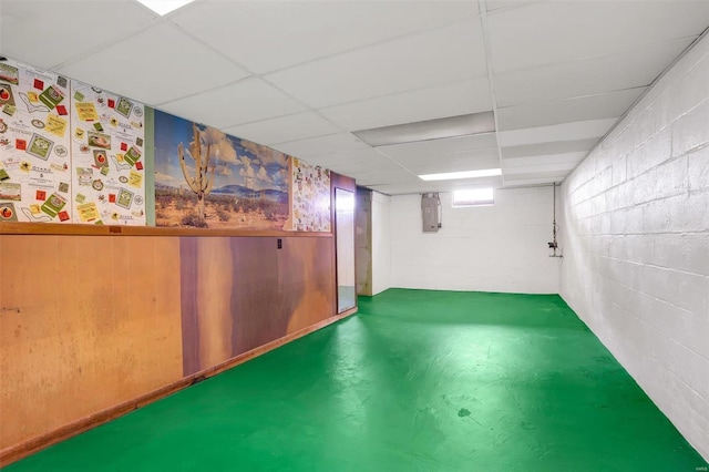 basement featuring a paneled ceiling and electric panel