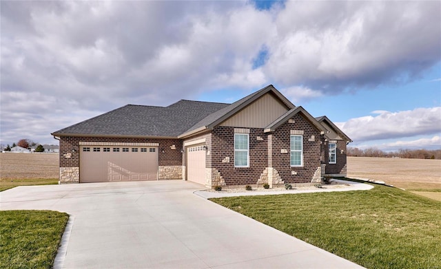 view of front facade with an attached garage, a shingled roof, a front lawn, concrete driveway, and brick siding