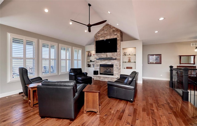 living area with visible vents, baseboards, a stone fireplace, and wood finished floors