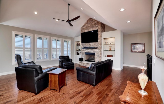 living area featuring built in shelves, a ceiling fan, wood finished floors, a fireplace, and baseboards