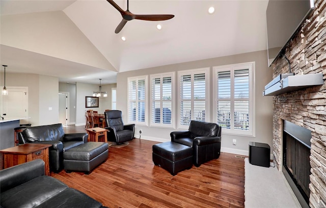 living room featuring a fireplace, baseboards, a ceiling fan, and wood finished floors