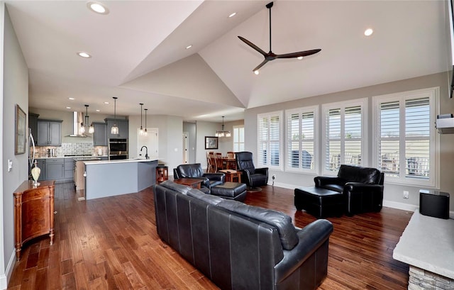 living area featuring dark wood-style floors, recessed lighting, ceiling fan with notable chandelier, and lofted ceiling