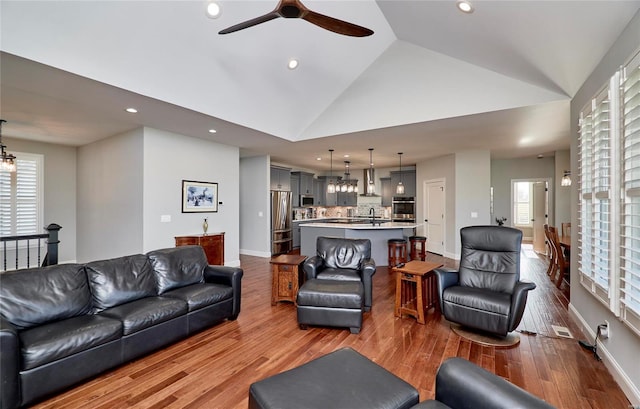 living room featuring dark wood finished floors, plenty of natural light, recessed lighting, and high vaulted ceiling