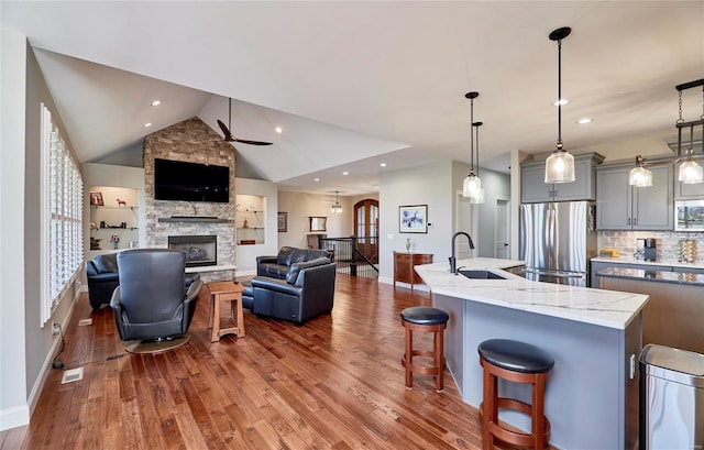 kitchen featuring open floor plan, gray cabinets, appliances with stainless steel finishes, a fireplace, and a sink