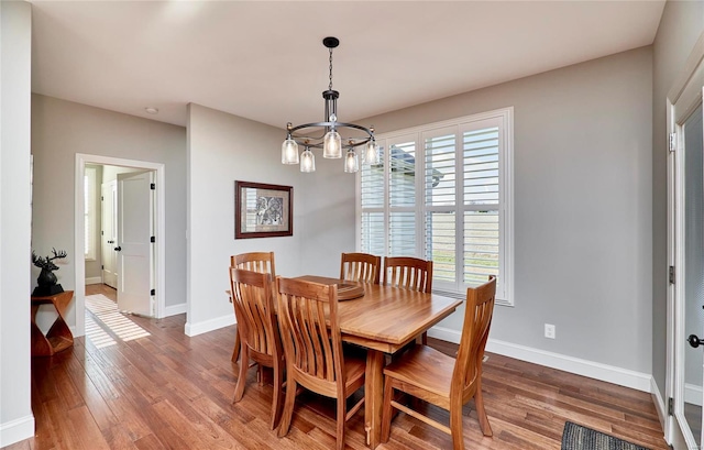 dining room with a chandelier, baseboards, and wood finished floors