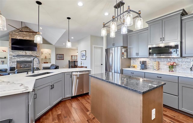 kitchen featuring a kitchen island, gray cabinets, stainless steel appliances, and a sink